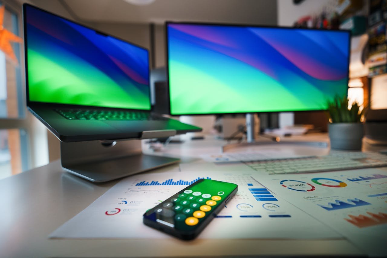 Contemporary office desk featuring a laptop, smartphone calculator app, and business graphs.